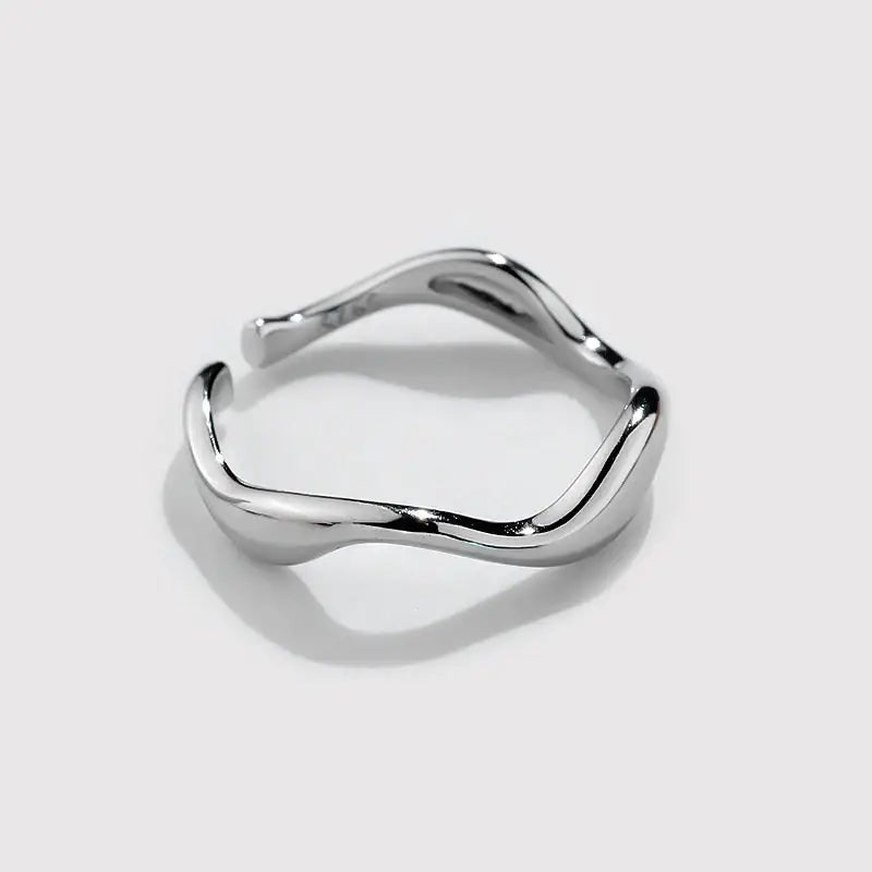 Silver ring with a wavy design on a white background
