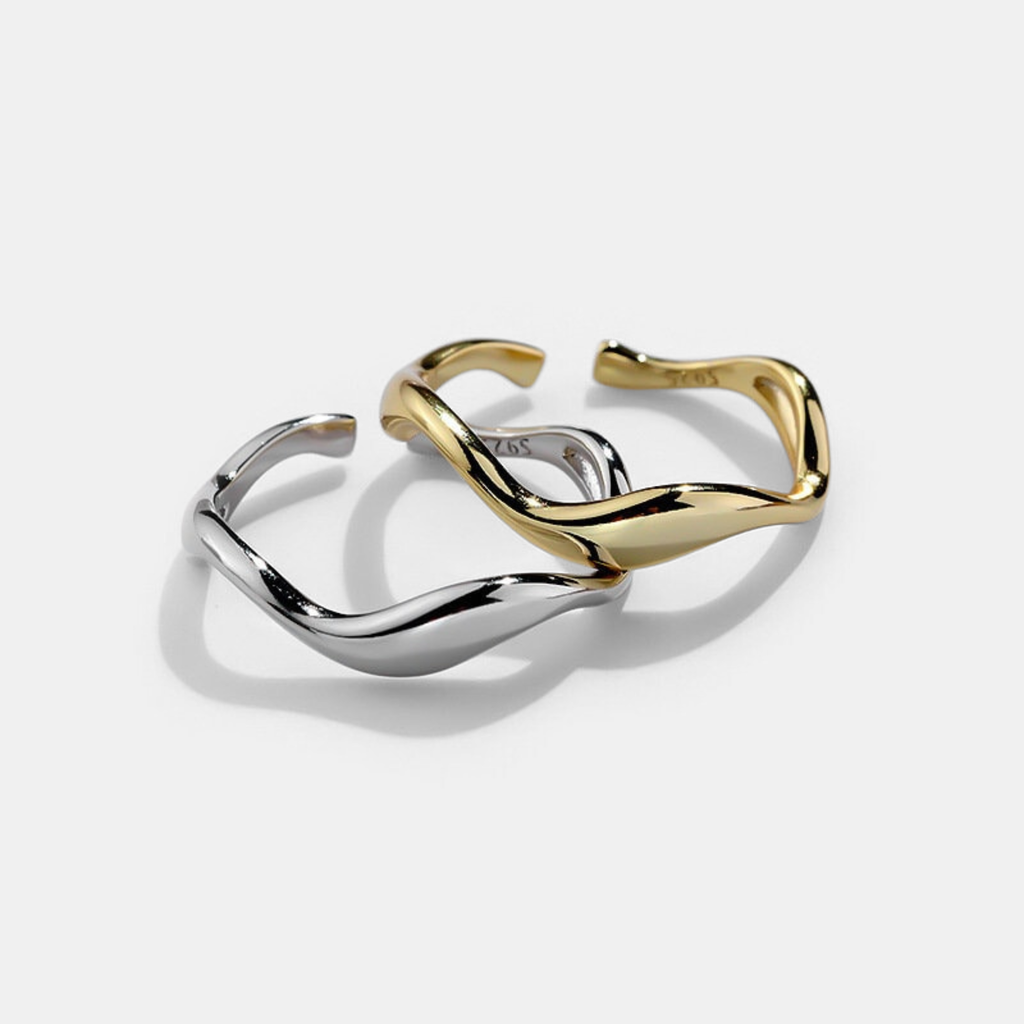 Two gold and silver cuff bracelets on a light gray background